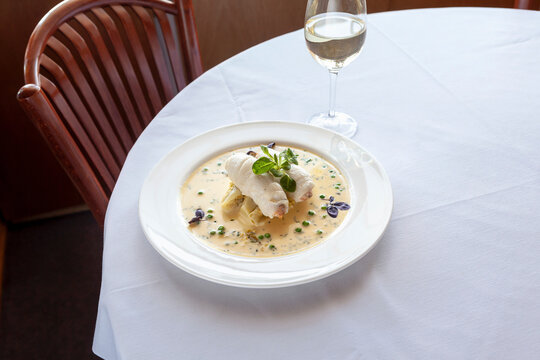 Fish rolls with crab stuffing and creamy sauce on white plate