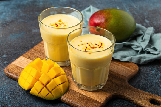 Mango lassi drinks garnished with saffron on wooden board