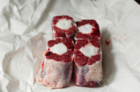 Raw sliced oxtail cuts with visible bone marrow on white paper
