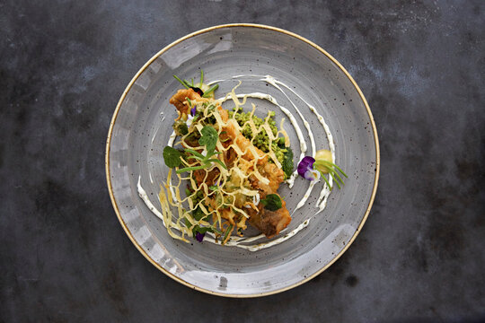Top-down view of fried sea fish with crushed peas and potato lattice