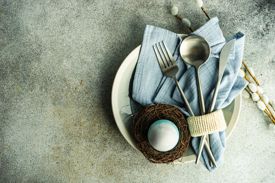 Easter dinner place setting with silverware and decorative easter egg