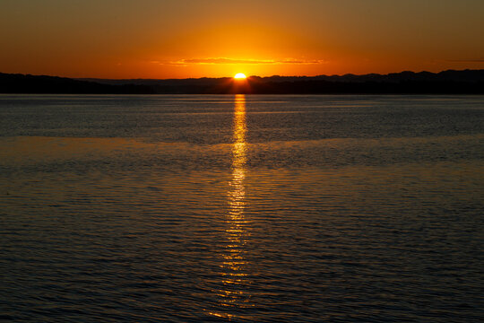 Sun setting over a calm lake with a golden reflection on the water, Peten, Flores, Guatemala