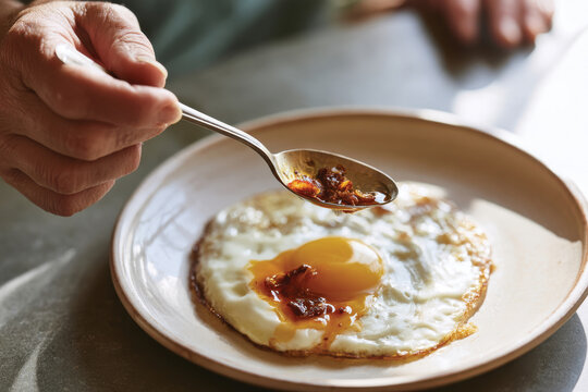 An inviting close-up of a fried egg on a plate with a drizzle of savory condiment, representing the joy of cooking, simplicity, and enjoying wholesome breakfast moments.