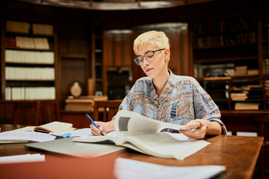 Woman studying and taking notes in library