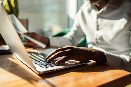 Man typing on laptop while reviewing a document