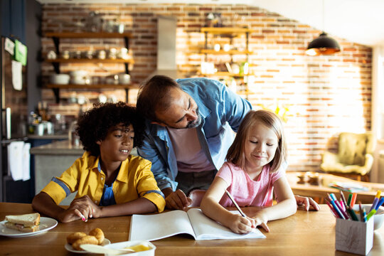Man helping children with homework at kitchen table