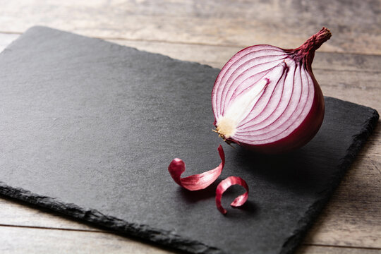 Halved red onion with purple rings on a dark slate board