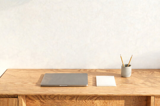 Closed laptop and blank notebook on a simple wooden desk