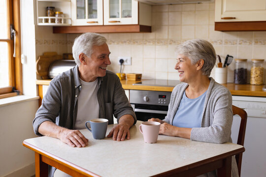 Senior man and woman talking over mugs at a kitchen table