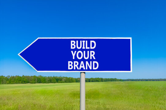 Build your brand words symbol. Concept words Build your brand on beautiful blue road sign. Beautiful blue sky green grass background. Business and build your brand concept. Copy space.