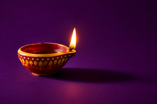 Single painted clay oil lamp shining on a purple background celebrating happy diwali and deepavali festival of lights during auspicious kali puja