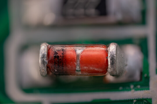 Macro close-up of a diode on an orange printed circuit board.