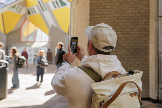 Man photographing Cube Houses with smartphone in Rotterdam