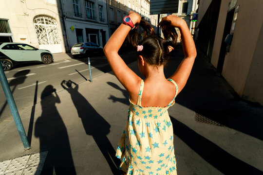 Child Walks in Street While Holding Hair up