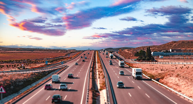  Tr&aacute;fico en la autopista, atardecer, cielo dram&aacute;tico, autom&oacute;viles, paisaje de autopista. Autopista transitada con tr&aacute;fico bajo un cielo dram&aacute;tico al atardecer. Representa viajes, transporte.